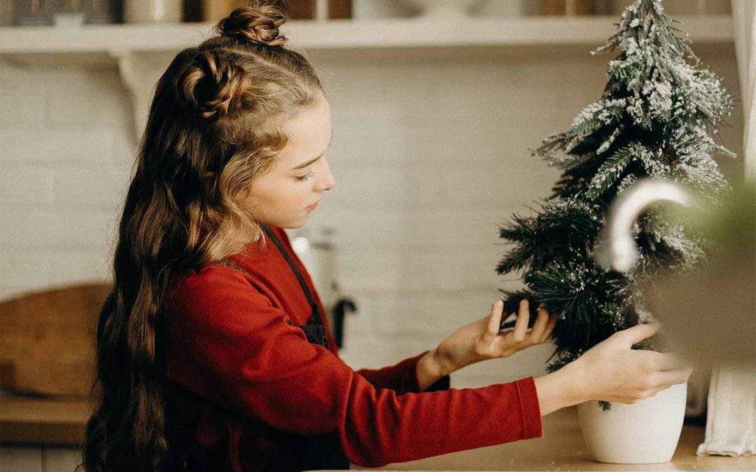 Girl decorating small Christmas tree indoors