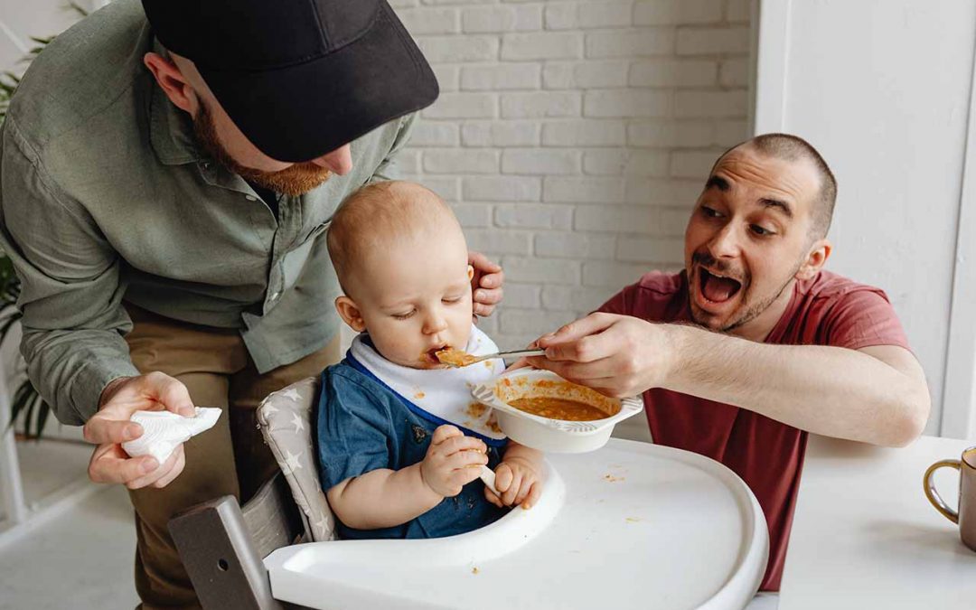 Toddler eating with two caregivers