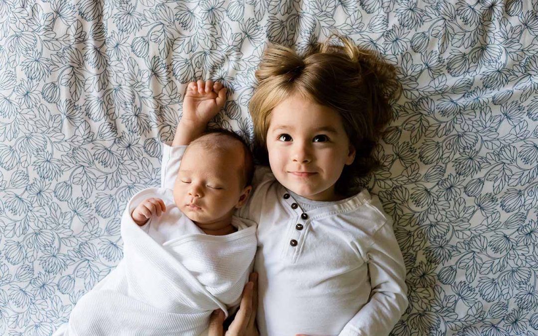 Siblings lying on floral bedspread